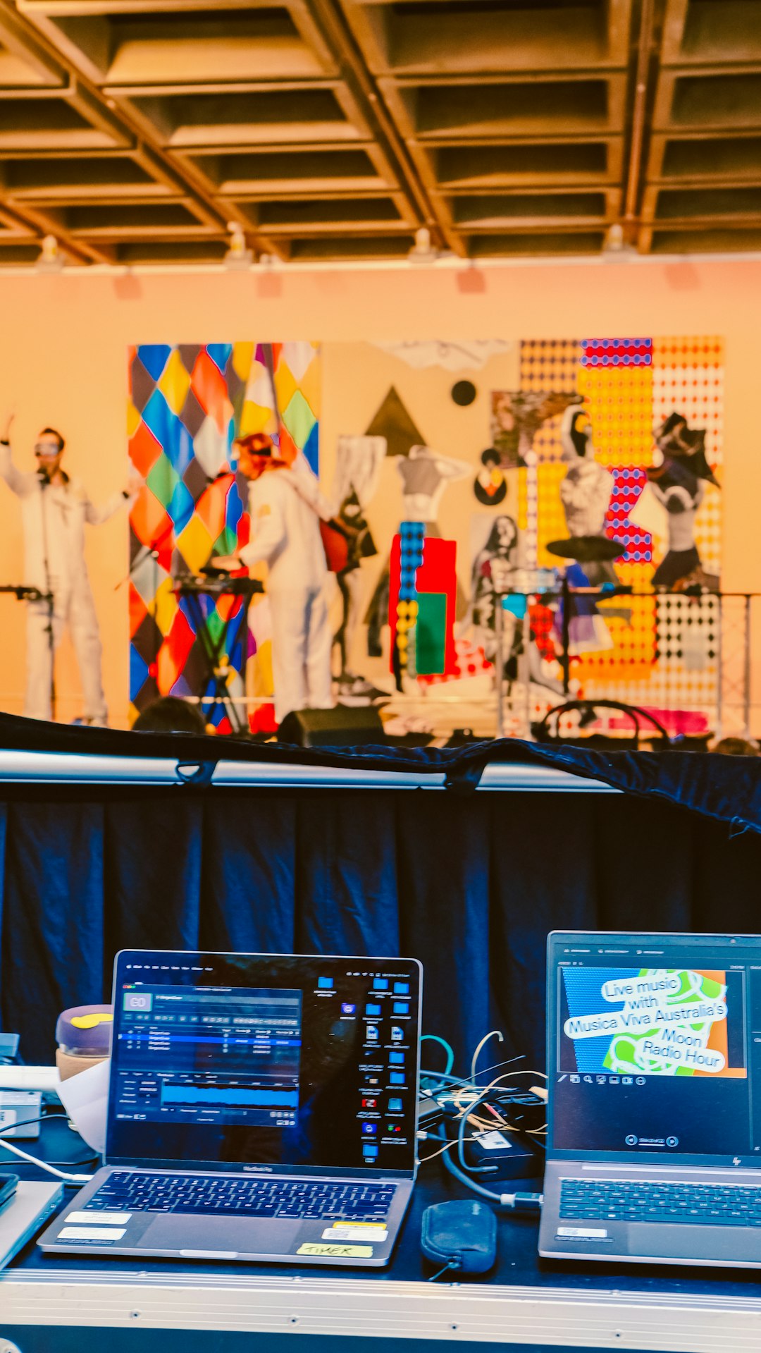 performers-on-stage-with-colorful-backdrop-and-laptops-in-foreground-3pl9-zmkok8